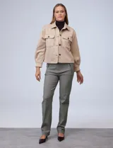 Chaqueta en símil suede color beige, con cuello de solapa y cierre frontal con botones, además de bolsillos en el frente.