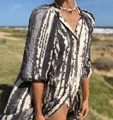 Vestido camisero con cuello a la base y mangas al codo, con botones al frente y estampado tie dye en tonos grises y blancos.