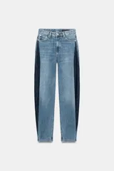 Jeans de tiro medio y corte barrel, confeccionados en denim de lavado celeste claro, con paneles laterales de denim azul oscuro a contraste. Presentan cinco bolsillos y cierre frontal con cremallera y botón.