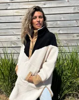 Buzo tipo poncho de polar color crudo con bloque superior en negro y detalles en beige.