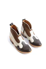 Botines de cuero marrón y blanco con diseño western, puntera redondeada y cierre lateral con cremallera. El talón tiene una tira de cuero para facilitar el calce.