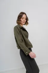 Chaqueta color beige de tela tipo gamuza con elastano, cuello solapa, manga larga con trabillas en hombro, bolsillos delanteros con cremallera metálica y cierre frontal con cremallera.