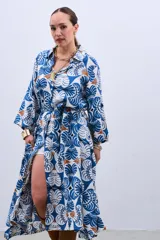 Vestido estilo camisola con estampado floral en tonos azules y marrones, con cuello camisero, mangas largas con puños y cierre frontal con botones. Incluye cinturón de la misma tela.