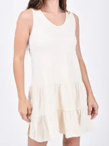 Vestido corto color coral, de corte suelto y sin mangas, con escote en V y falda escalonada con volantes.