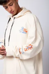 Buzo canguro amarillo ocre oversize de algodón rústico con capucha, cordones negros con letras blancas, bolsillo frontal y puños y cintura acanalados. Presenta estampados en el frente y las mangas.