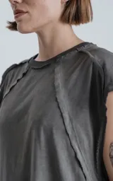 Remera gris con cuello redondo y sisas amplias, con recortes en delantero y mangas y efecto gastado.