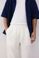Pantalón blanco de lino liviano, corte recto, con elástico revestido y cordón ajustable en la cintura, bolsillos laterales y bolsillo trasero insertado.