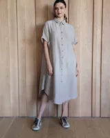 Vestido túnica color beige, de lino, con cuello camisero, manga corta y cierre frontal con botones.