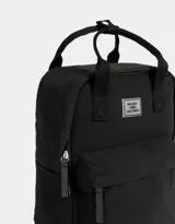 Mochila negra de tela deportiva con correas regulables, manijas superiores con broche, acceso con cierre superior y puller de cuerina, bolsillo frontal con cierre y puller de cuerina, y tag de goma.