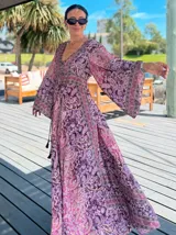 Vestido largo de polysilk con estampado paisley en tonos azul, celeste y dorado. Tiene escote en V, mangas largas acampanadas y corte amplio.