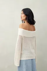 Sweater color crema, tejido de punto calado, con escote off-shoulder y mangas largas acampanadas.