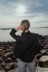 Blusa negra de lino con cuello mao, mangas largas y alforzas verticales en el frente.