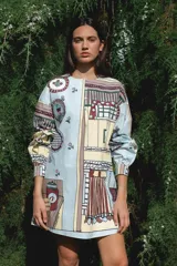 Vestido corto celeste con estampado de objetos y flores, manga larga abullonada con puño elastizado y cierre frontal con botones.