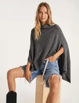 Poncho tejido de punto liso, color gris oscuro, con cuello vuelto y aberturas laterales para los brazos.