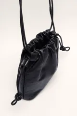 Cartera tipo pouch negra de cuero ovino con correa ajustable para usar al hombro o cruzada. Tiene bolsillo interno y forro textil.