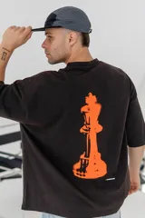 Remera color beige con estampado de una pieza de ajedrez en color naranja en la espalda.