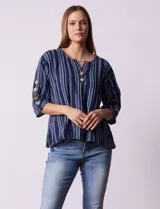 Blusa de algodón a rayas azules y blancas, con cuello a la base, escote en V con botones y mangas 3/4 con aplique de botones.