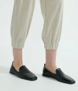 Pantalón jogger color beige, con elástico en la cintura y en los tobillos, cordón ajustable, bolsillos laterales y detalles de agujeros en los laterales y en los bolsillos.