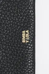 Billetera de cuero sintético color blanco con textura granulada. Tiene cierre con solapa y botón a presión, múltiples compartimentos internos para tarjetas y billetes, y un bolsillo con cierre para monedas. Incluye una correa de mano extraíble.