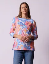 Blusa de algodón con estampado de flores en tonos rosa, naranja, azul y blanco. Tiene cuello cuadrado con borde celeste y mangas 3/4 con borde celeste.