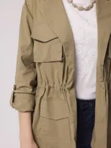 Campera color beige, estilo cazadora, con cuello camisero, cierre frontal con botones, cuatro bolsillos frontales con solapa y mangas 3/4 con trabillas.