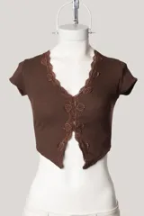 Remera corta negra de tejido acanalado, con escote en V y detalle de puntilla en el borde.