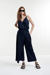 Mono azul marino con breteles finos, corte a la cintura y pantalón palazzo con diseño cruzado y lazo lateral.