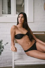 Conjunto de bikini negro con lunares marrones. El corpiño es tipo bandeau con piedra en el centro y espalda fija. La bombacha es colaless con piedra en el lateral.