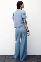 Pantalón celeste de tiro alto con cintura elástica ajustable con cordones, bolsillos delanteros y traseros, y pernera ancha.