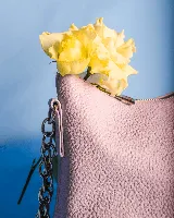 Cartera amarilla de cuero con forma de media luna, cierre superior y correa de cadena plateada.