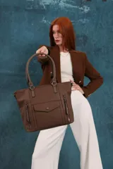 Cartera bandolera de símil cuero color marrón claro, con doble asa rígida y correa regulable. Presenta dos bolsillos frontales con cierre vertical y un bolsillo frontal con solapa y botón. Cuenta con dos divisiones internas.