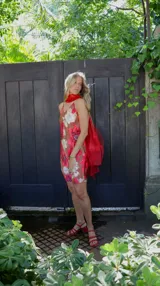 Vestido corto con estampado floral en tonos rosados y blancos sobre fondo marrón. Diseño con breteles finos y corte recto.