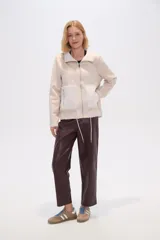 Campera color beige de corte recto, con cuello de piel sintética, cierre frontal con cremallera, bolsillos laterales con cremallera y cordón ajustable en el ruedo.