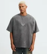 Remera oversized masculina de media malla con toque gamuza, color gris oscuro con efecto lavado. Presenta un bordado blanco en forma de media luna en el pecho y un estampado lettering en la parte delantera y trasera.