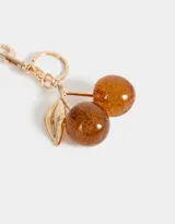 Llavero con dije de cerezas color marrón con glitter dorado, hojas doradas y mosquetón metálico dorado.
