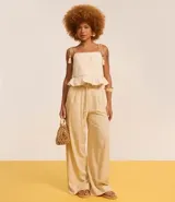 Pantalón pantalona color beige confeccionado en viscolino con viscosa certificada, con cintura con trabillas, cierre tradicional, cinturón de cuerda encapado con hebilla contrastante de adornos, esferas en las puntas y pliegues.