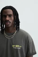 Camiseta negra con efecto lavado, cuello redondo, manga corta y estampado en el frente con la frase "Don't miss out! One Night. One Stage.".