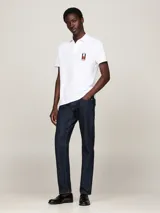 Chomba blanca de piqué de algodón con cuello clásico, cartera de dos botones y logo vertical de Tommy Hilfiger bordado en el pecho. Corte regular.