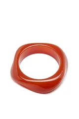 Brazalete rígido color naranja con forma geométrica irregular.