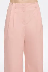 Pantalón tobillero de algodón de corte recto color rosa, con cierre frontal de corchete oculto y cremallera, pinzas en la parte delantera y presillas de tela. Presenta bolsillos diagonales delanteros y bolsillos traseros con vivo.