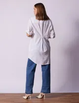 Camisola larga de algodón color blanco, marca Dash. Tiene cuello con solapa, abertura central con botones, bolsillo aplicado en el pecho, mangas regulables con presilla y botón, y bolsillos laterales en la costura.