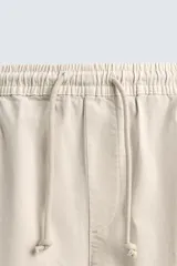 Pantalón cargo slim fit negro con cintura elástica ajustable con cordón, bolsillos frontales, traseros y laterales con solapa. Bajo con puño elástico.