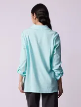 Camisa celeste texturada con cuello con solapa y abertura central con botones. Delantera con bolsillo aplicado y largo de manga regulable con presilla y botón.