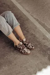 Zapatillas bajas de cuero color marrón con suela de goma color caramelo y cordones marrones.