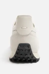 Zapatillas deportivas color crema con cordones, estilo retro. Parte superior fabricada en tejido técnico y detalles en piel con acabado serraje. Suela dentada con detalle a contraste en negro.