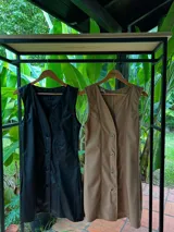 Vestido corto tipo jumper de cuerina color negro, con escote en V y abotonadura frontal. Sin mangas.