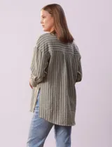 Blusa verde con rayas verticales blancas, cuello a la base y escote en V con aplique de botones. Manga ¾ con puño y botón. Tajo en costuras laterales.