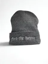 Gorro de lana sintética gris con la frase "Feed the Haters" bordada en blanco en el borde.