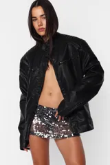 Campera de cuero sintético negro, corte oversize, cuello mao con broche, cierre metálico frontal, bolsillos con cierre, hombreras matelaseadas, puños con cierre y forro matelaseado.