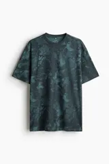 Remera deportiva de poliéster color verde con estampado abstracto, corte holgado, mangas cortas y cuello redondo.